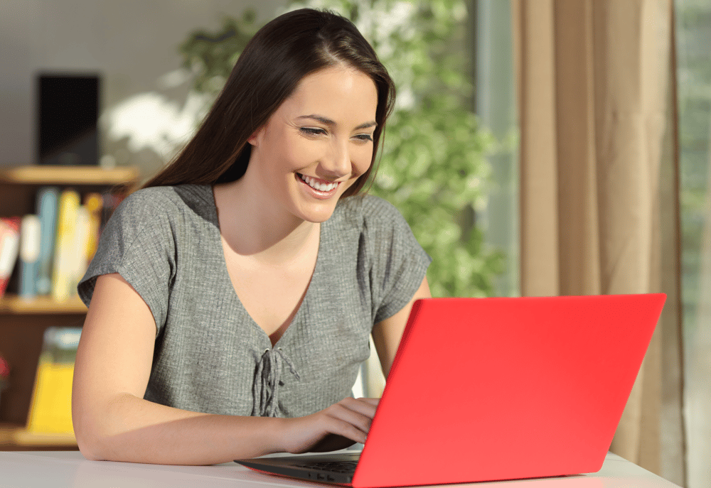 A charity employee working efficiently on a red laptop after teaming up with experts in response handling for charities.