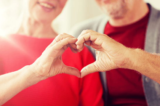 A close-up of senior couple showing hand heart sign, representing the charity supporter journey