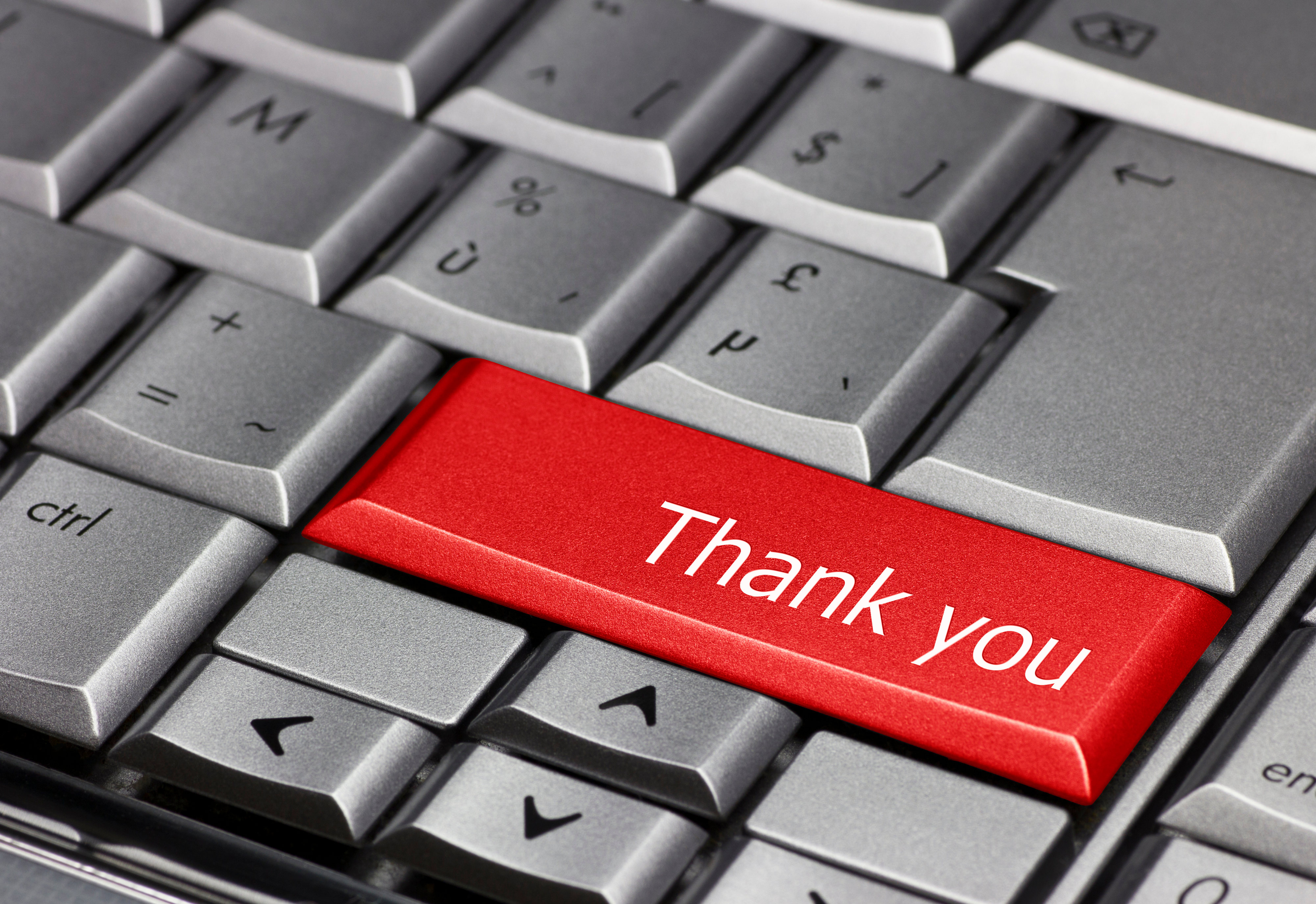 A metallic silver keyboard with a red key displaying the words thank you, representing the importance of thanking as part of fundraising strategies.
