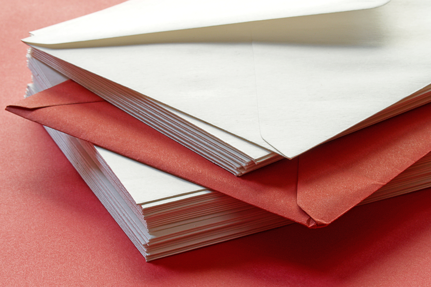 A stacked pile of post mail on a red table to represent charity response handling