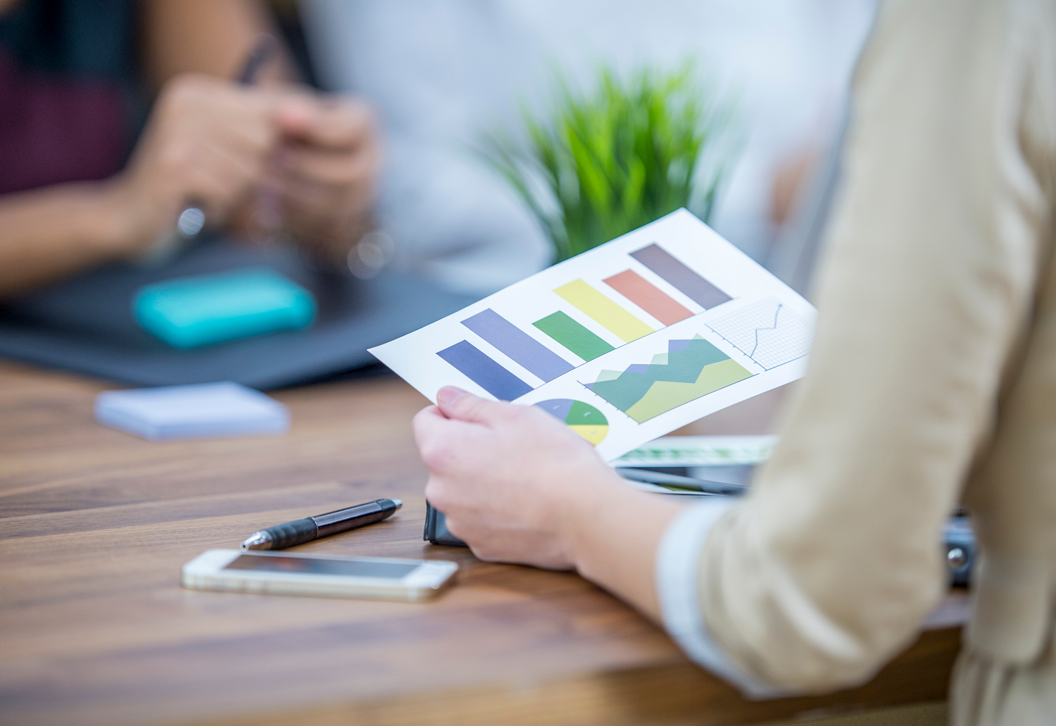 A woman holding a piece of paper displaying bar charts and graphs, representing prize-led charity fundraising trends.