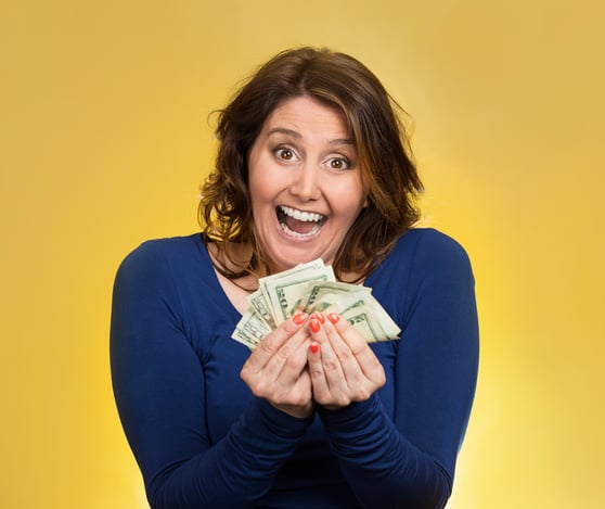 Closeup portrait super happy excited successful middle aged business woman holding money dollar bills in hand isolated yellow background. Positive emotion facial expression feeling. Financial reward