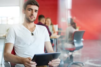 Confident male designer working on a digital tablet in red creative office space-1