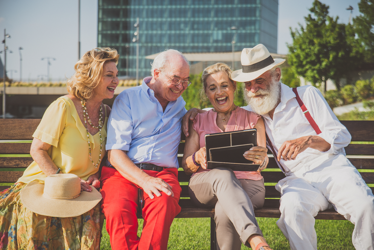 Group of senior people sat on a bench outdoors looking at a tablet, representing the charity supporter journey