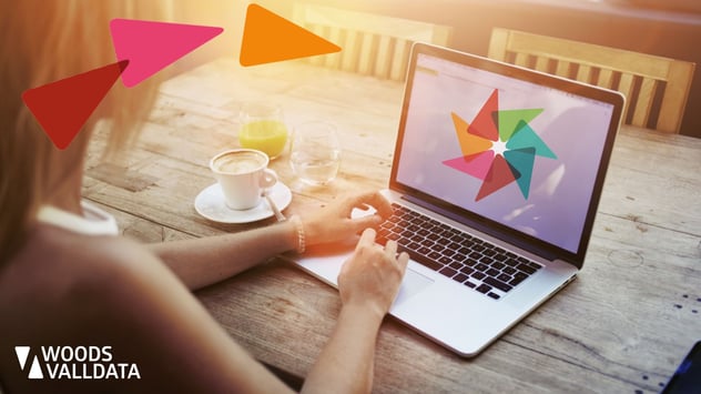 Laptop on a wooden table with coffee cup and orange juice and womans arms and hands typing banner WV brand