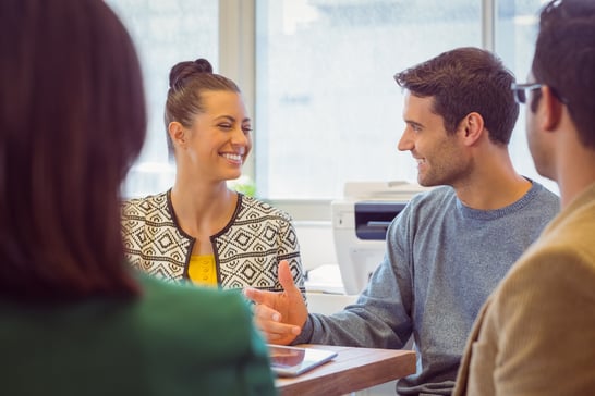 Smiling colleagues talking together in the office showing collaboration between different organisational departments