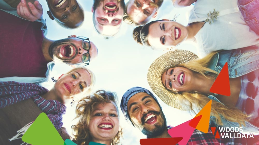 A group of young people standing in a circle and smiling down at the camera, representing supporters engaged through lottery funding for charities.