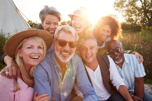 group of happy middle aged people of multi ethnic backgrounds in a field on a summers day looking at camera and smiling